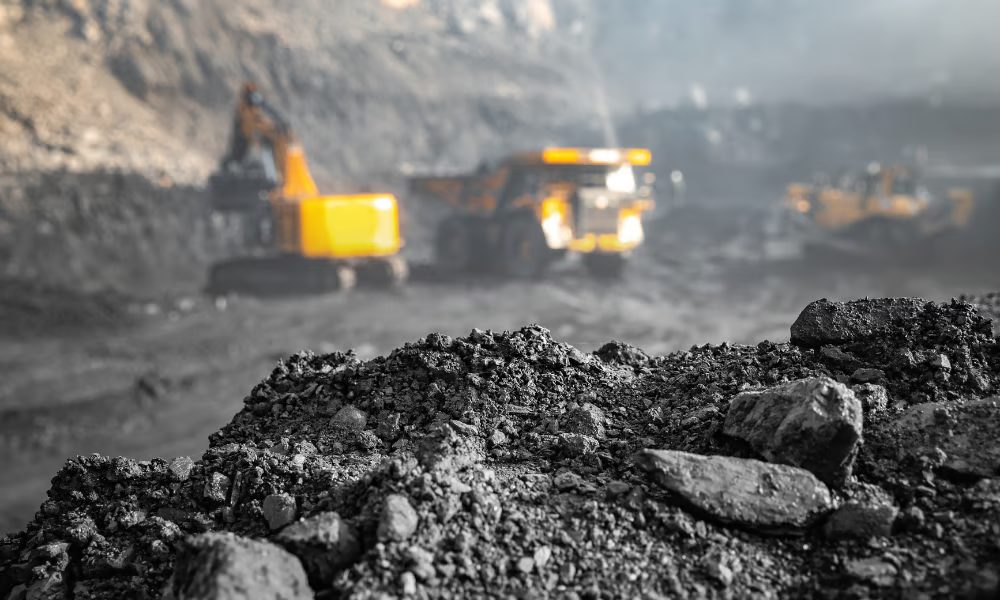 Coal mine with an excavator and haul trucks behind a pile of coal